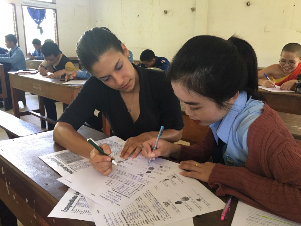A female teacher helps a student with her English writing.